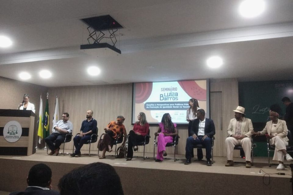 Palco composto por diversas pessoas sentadas em suas respectivas cadeiras